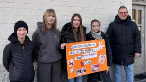 Schülerinnen und Schüler der Hellweg RealSchule überreichen der Aids Hilfe Unna einen symbolischen Scheck